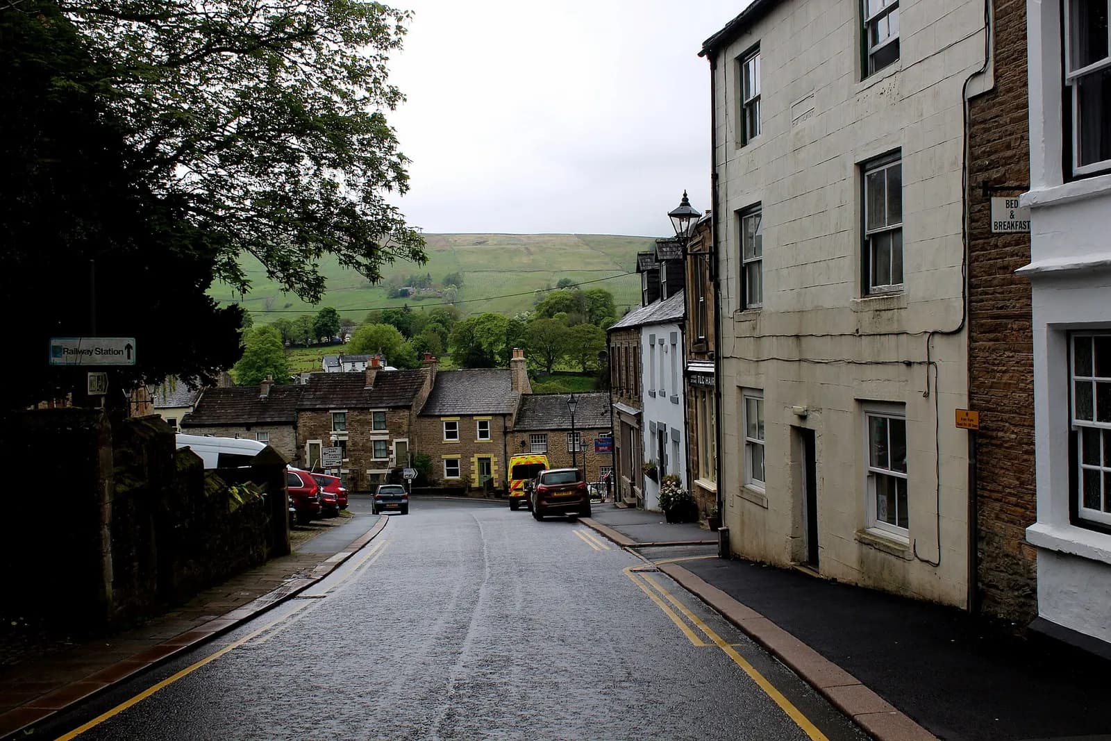 Stone houses lining a steep street in Alston with North Pennine hills beyond