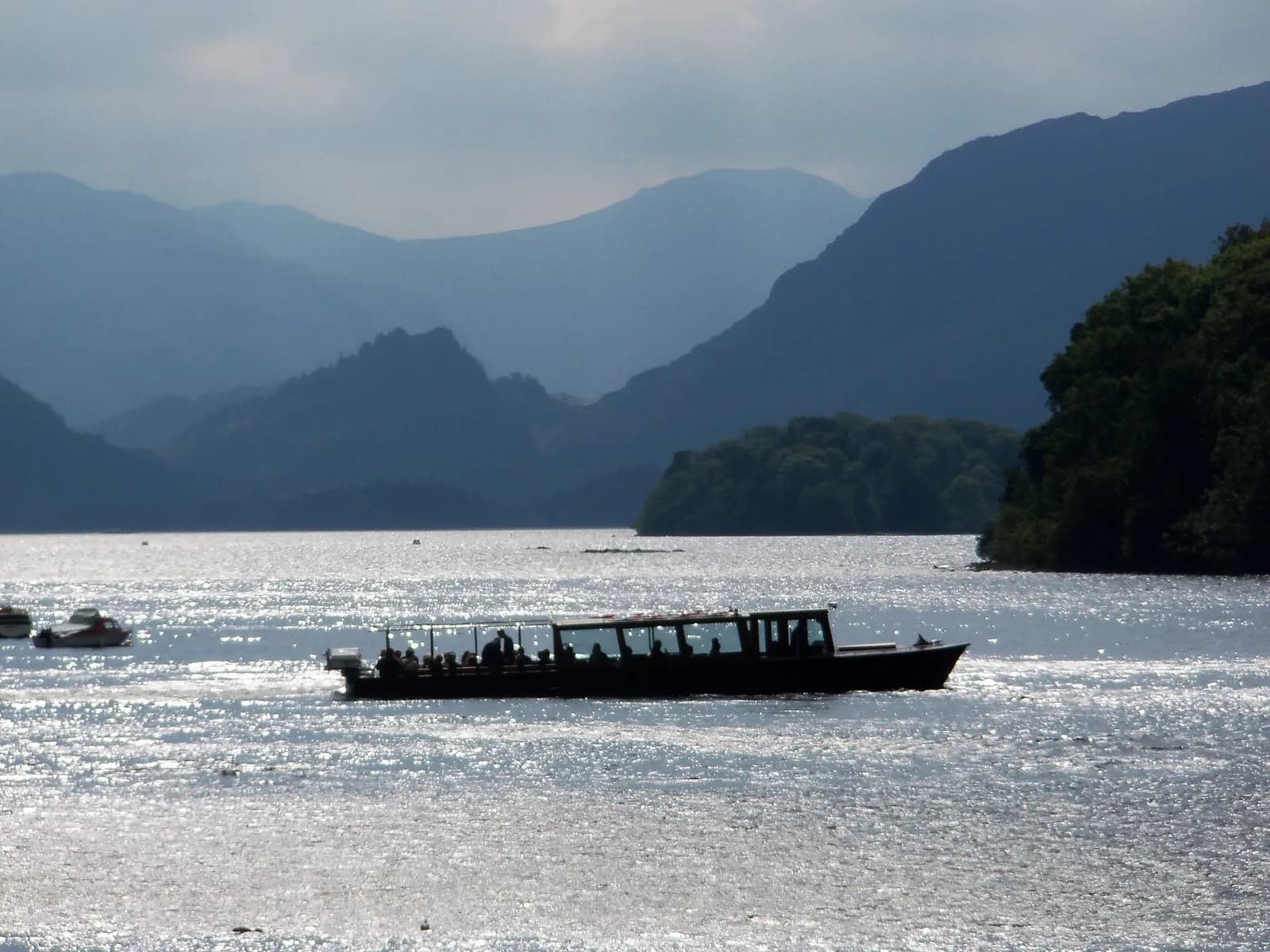 A launch crossing Derwentwater towards the wooded Jaws of Borrowdale and Castle Crag