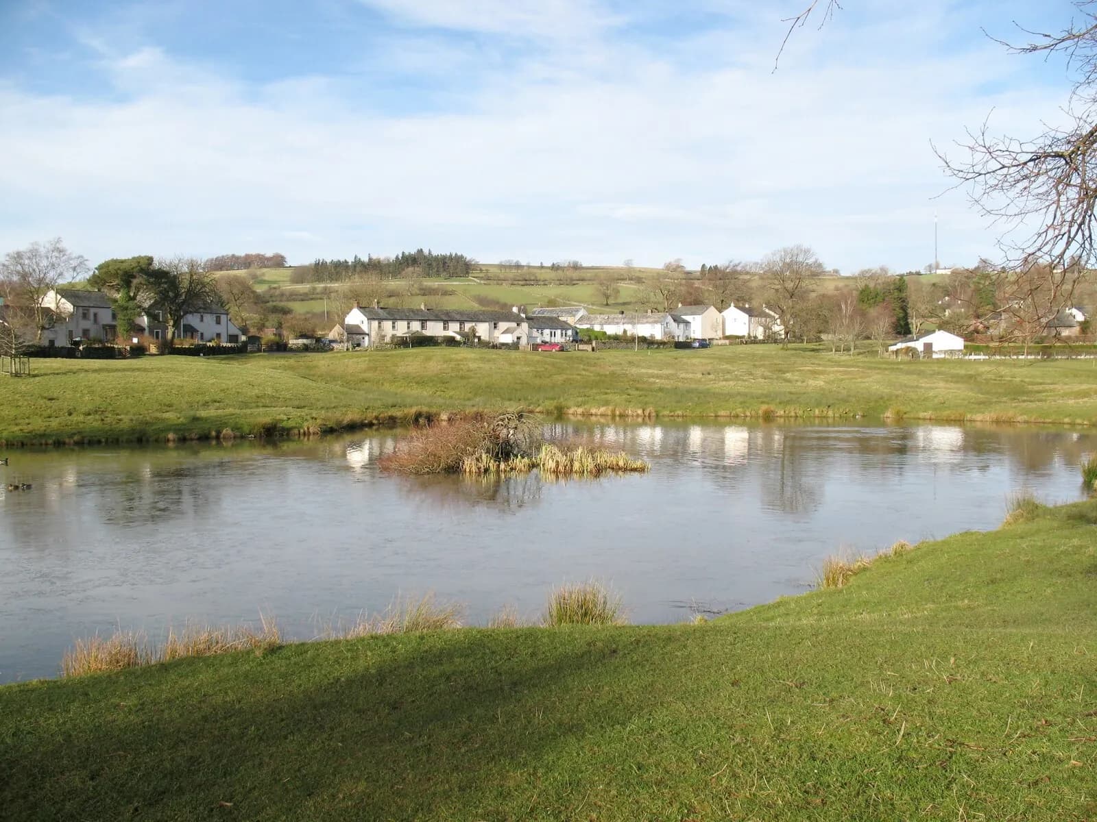 The village pond at Caldbeck with whitewashed cottages and farmland beyond