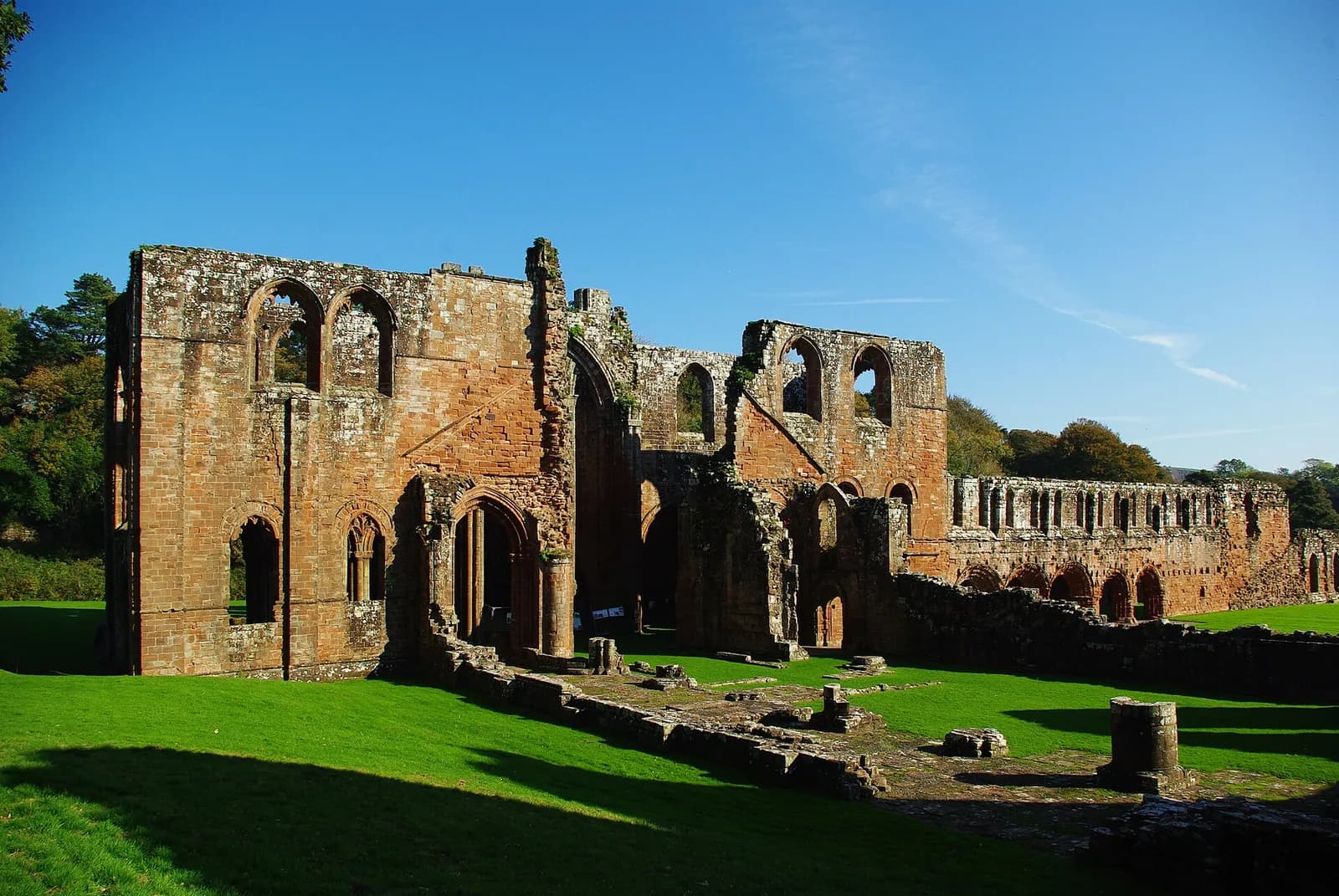 The red sandstone arches and ruined nave of Furness Abbey on a sunny day