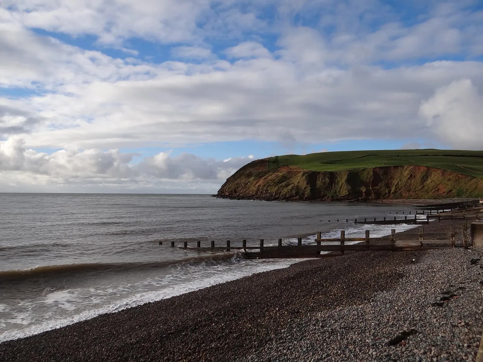 The red sandstone cliffs of St Bees Head above the shingle beach and groynes