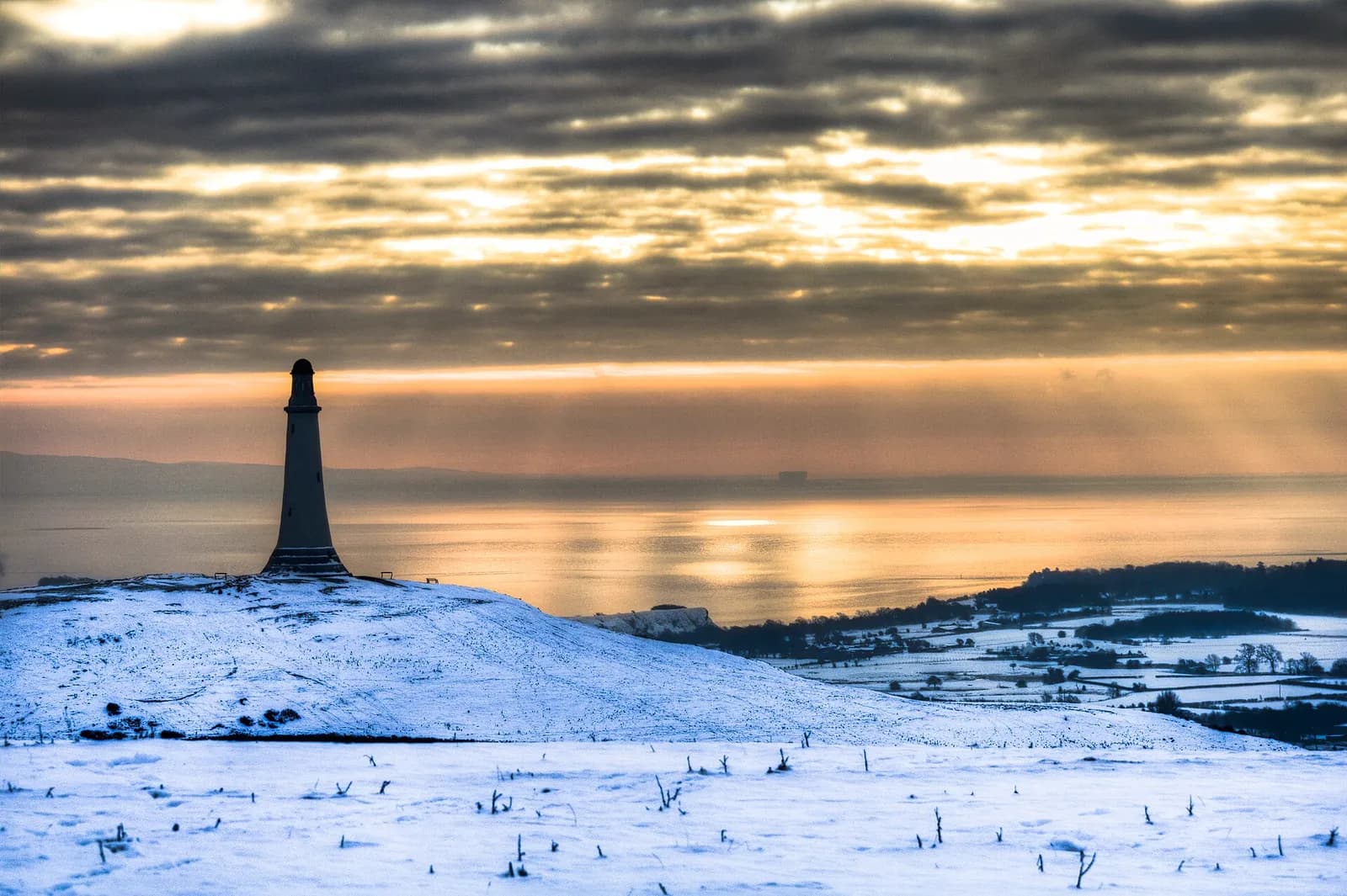 The Hoad Monument on snow-covered Hoad Hill above Ulverston with Morecambe Bay beyond