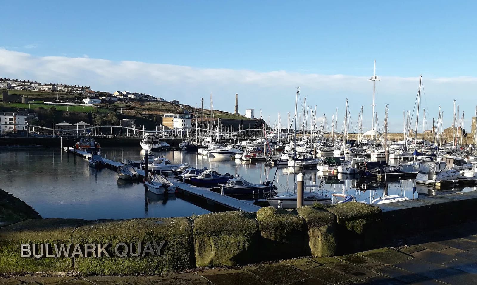 Yachts moored in Whitehaven marina below the town's terraces and hillside