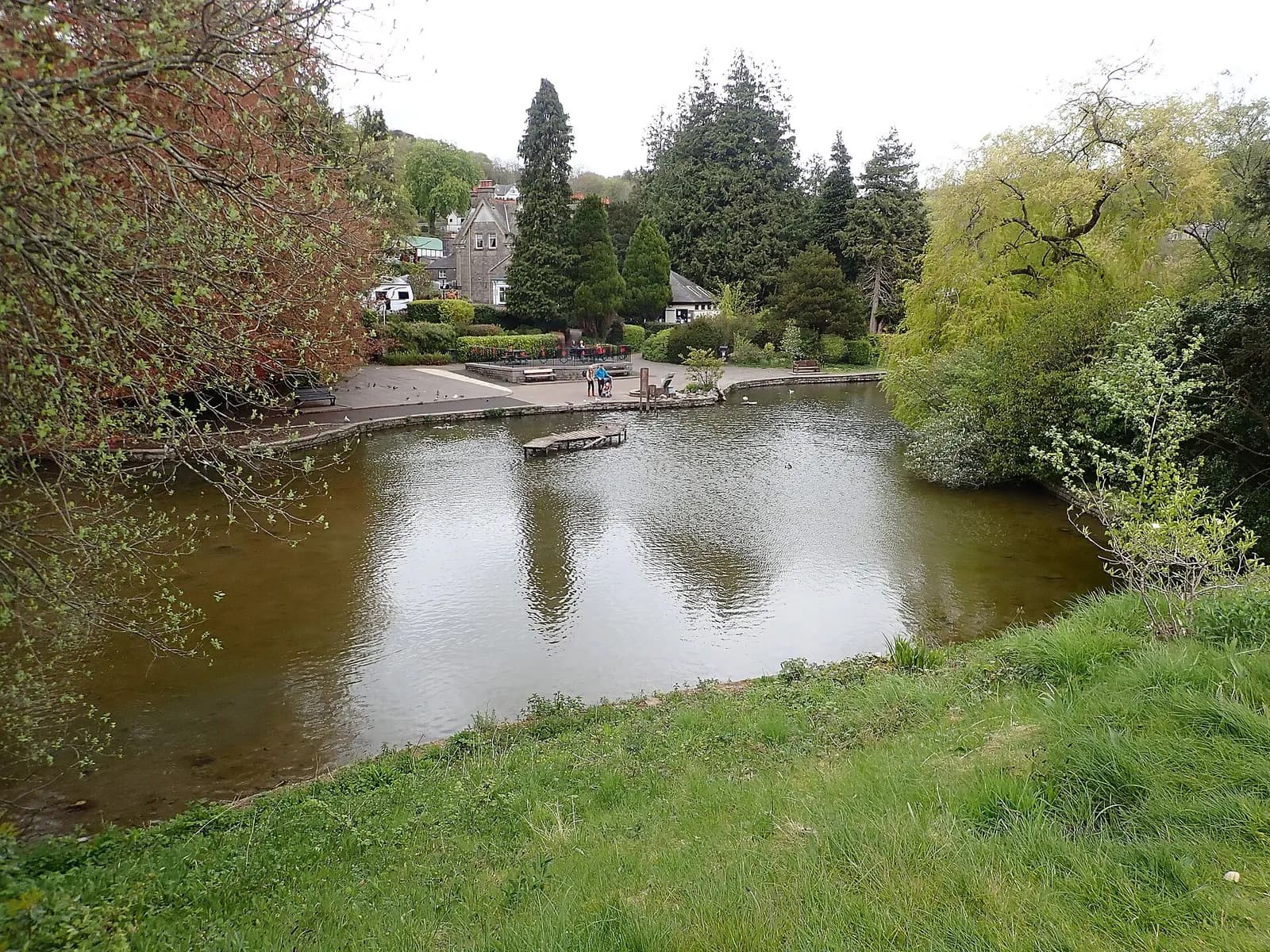 The duck pond in Grange-over-Sands ornamental gardens framed by trees and Victorian villas