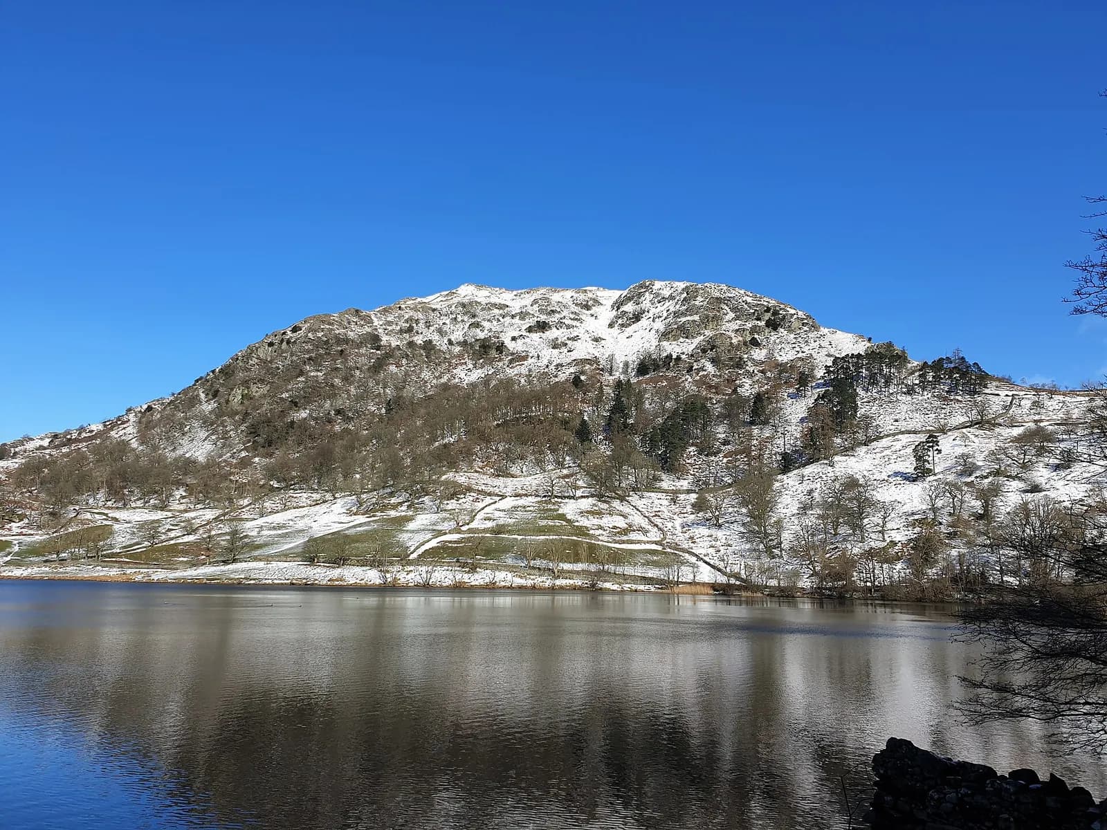 Snow-dusted Nab Scar rising above the still surface of Rydal Water