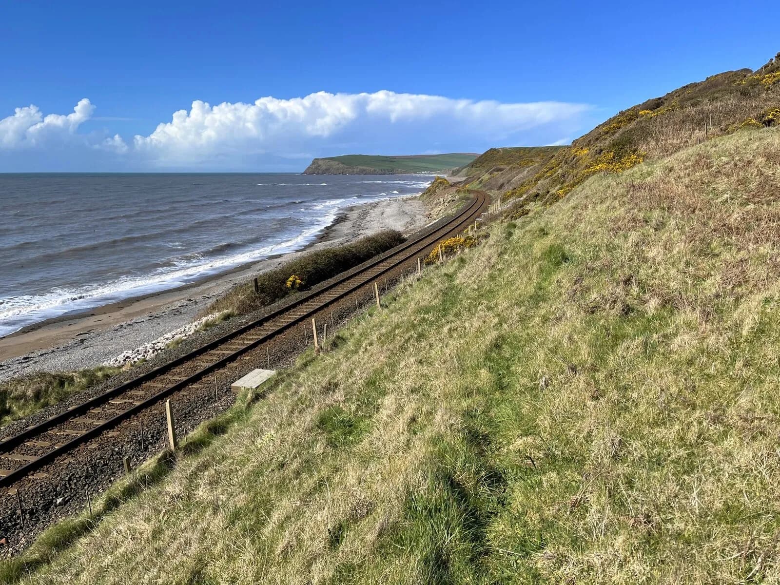 The Cumbrian Coast railway running beside the shore towards a distant sandstone headland