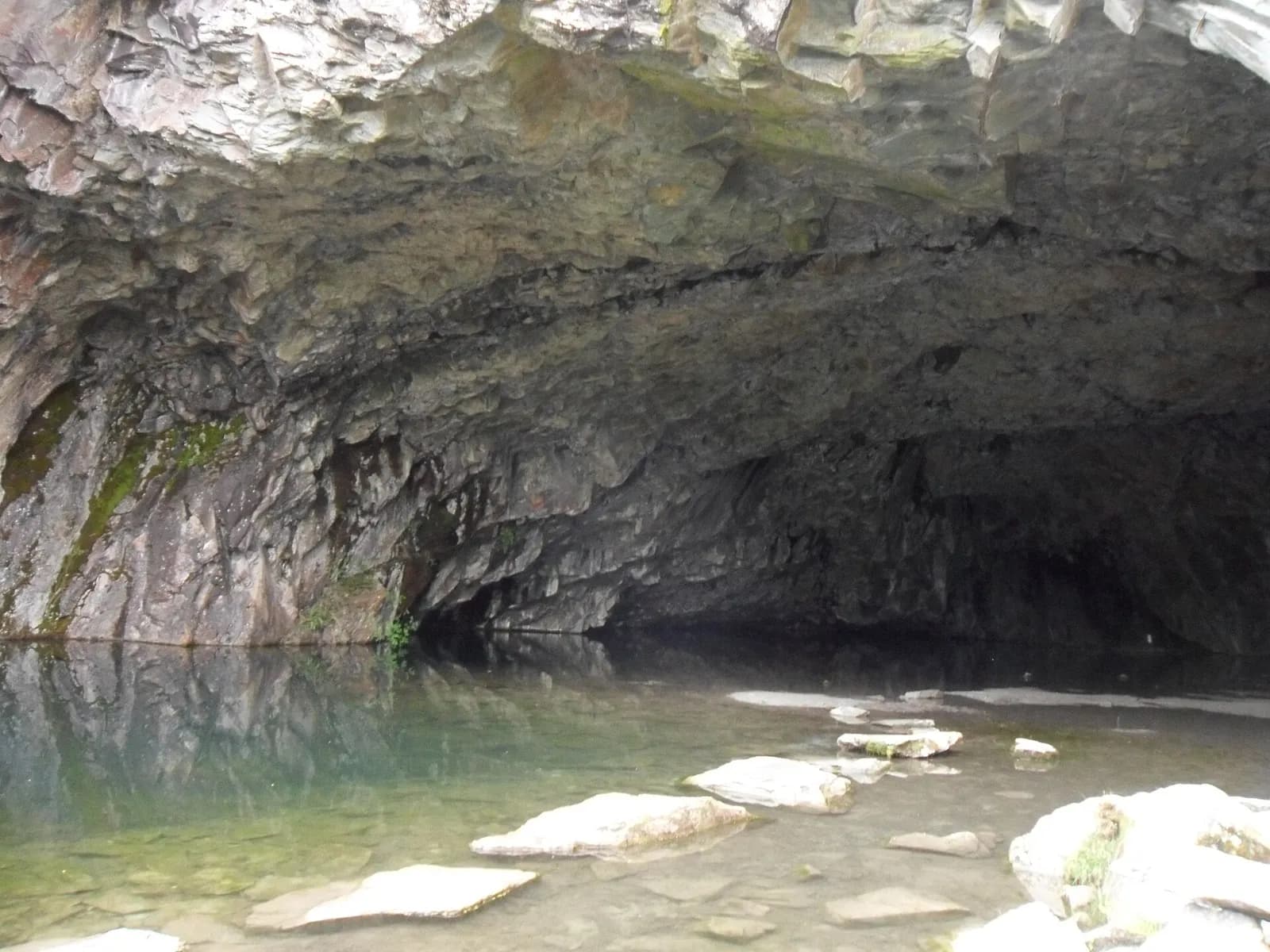Inside the great slate-quarry chamber of Rydal Cave, with stepping stones across its shallow pool