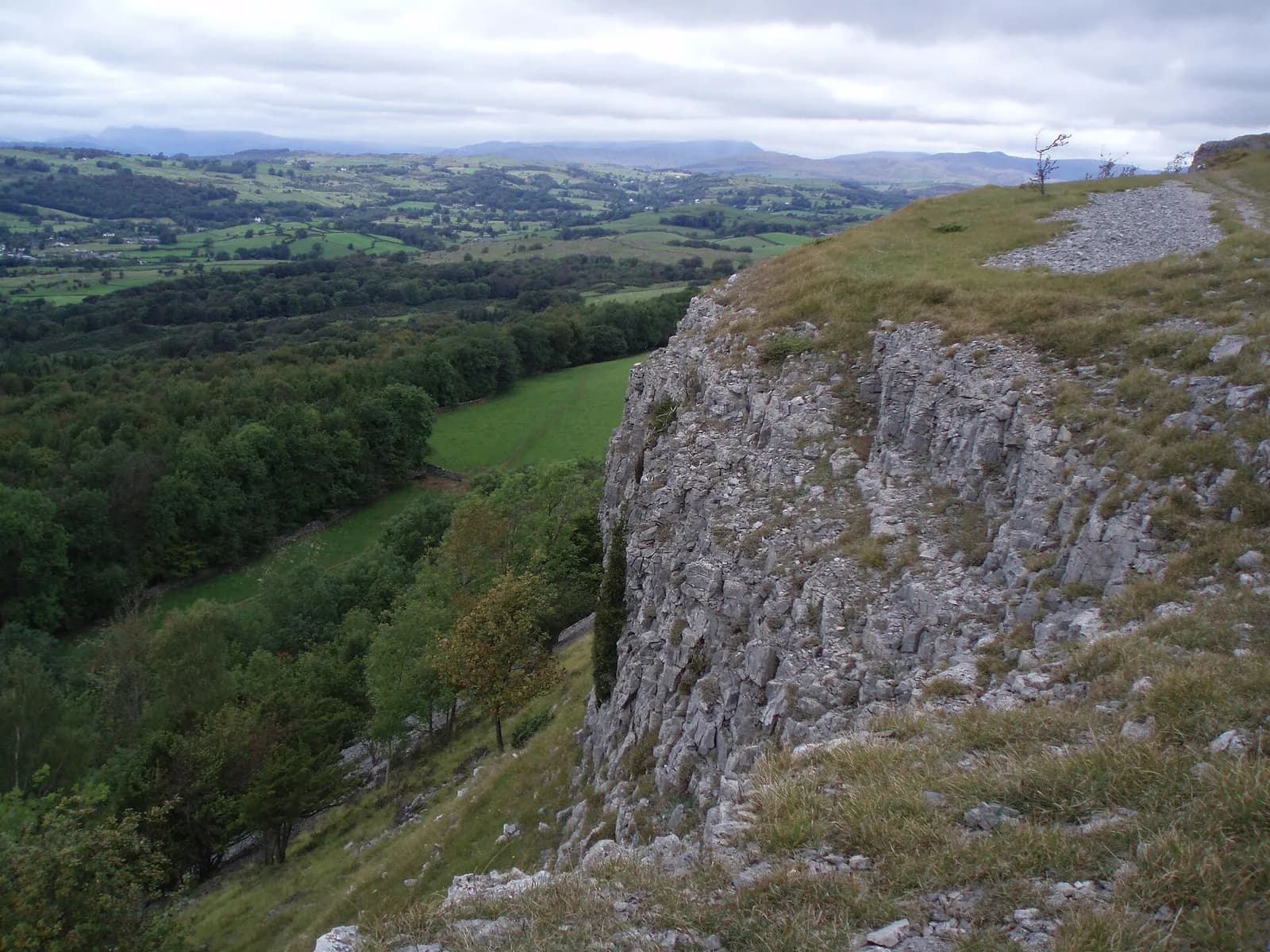 The limestone cliff of Scout Scar above wooded farmland